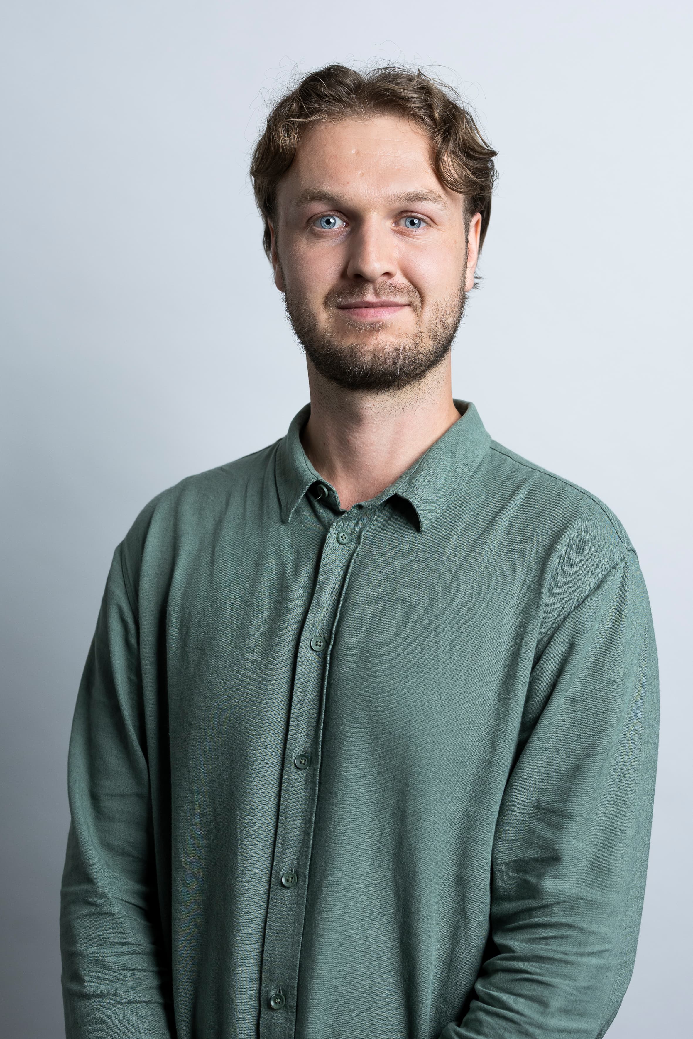Porträt einer Person in einem hellgrünen Hemd vor einem hellgrauen Hintergrund. Die Person blickt direkt in die Kamera. Die Aufnahme zeigt den Oberkörper und ist professionell ausgeleuchtet.